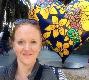 A picture of the author in front of one of the Hearts in San Francisco sculptures - a large navy blue heart with vivid yellow flowers
